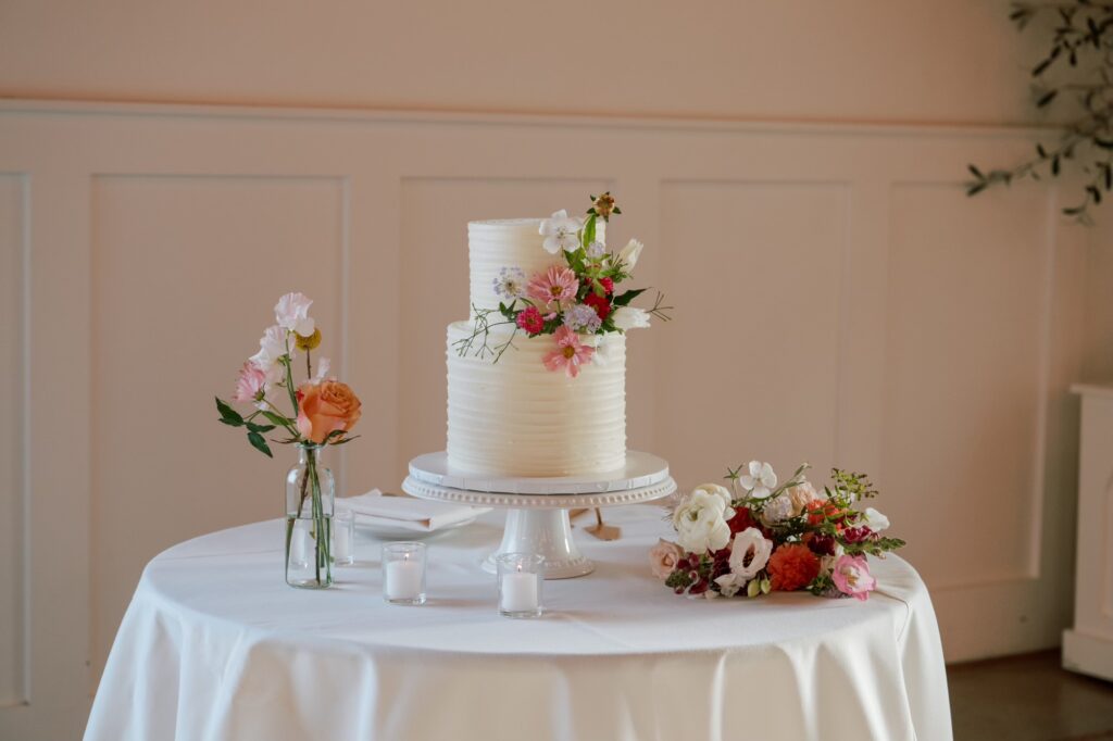 Elegant two-tiered white cake adorned with fresh flowers sits on a table